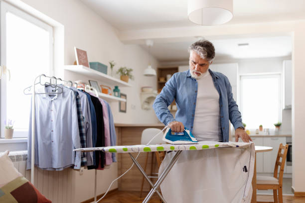 housework and household concept man ironing shirt on iron board at home